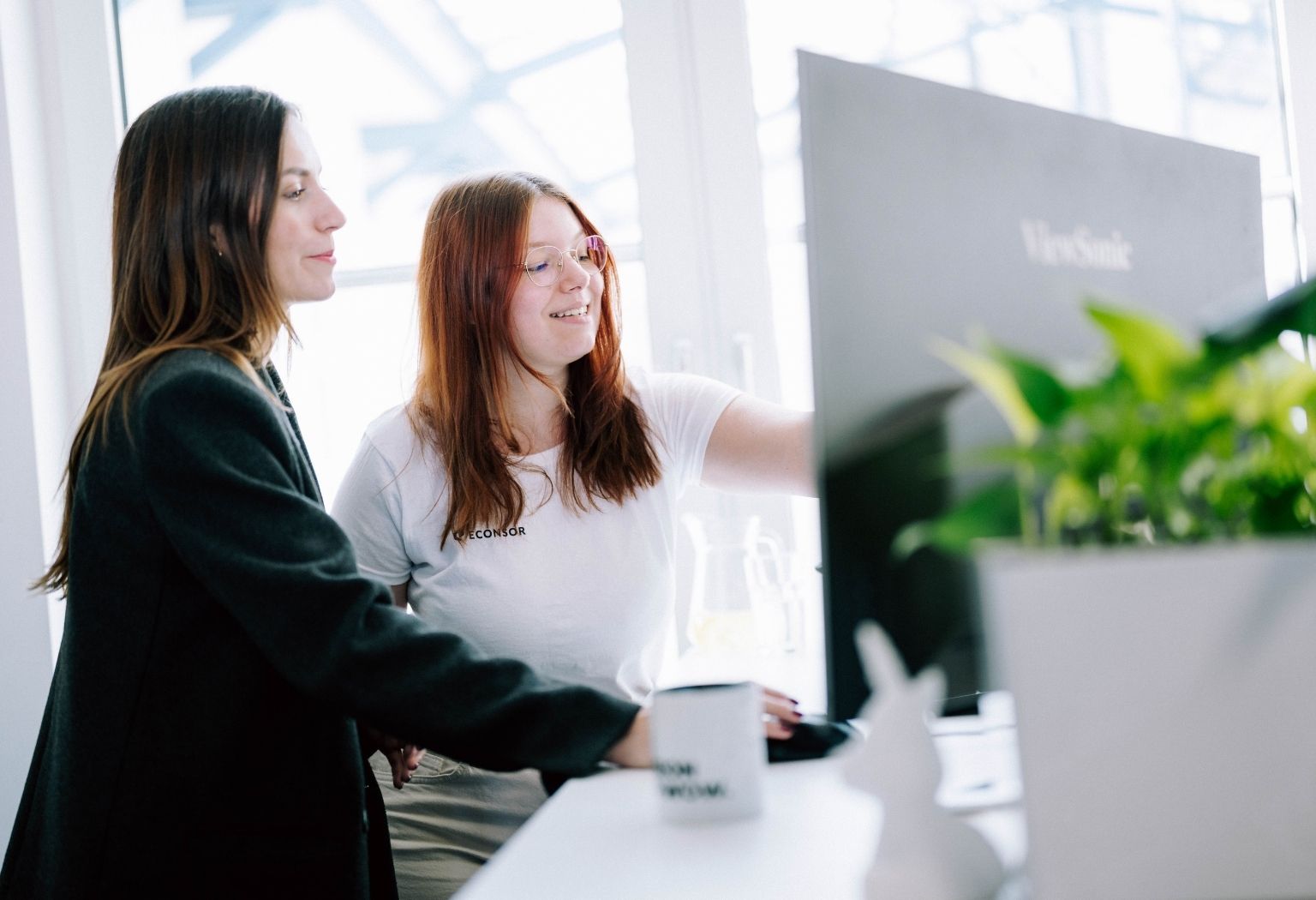 Zwei Frauen analysieren einen Computerbildschirm, der Informationen zu Online-Marketing zeigt.